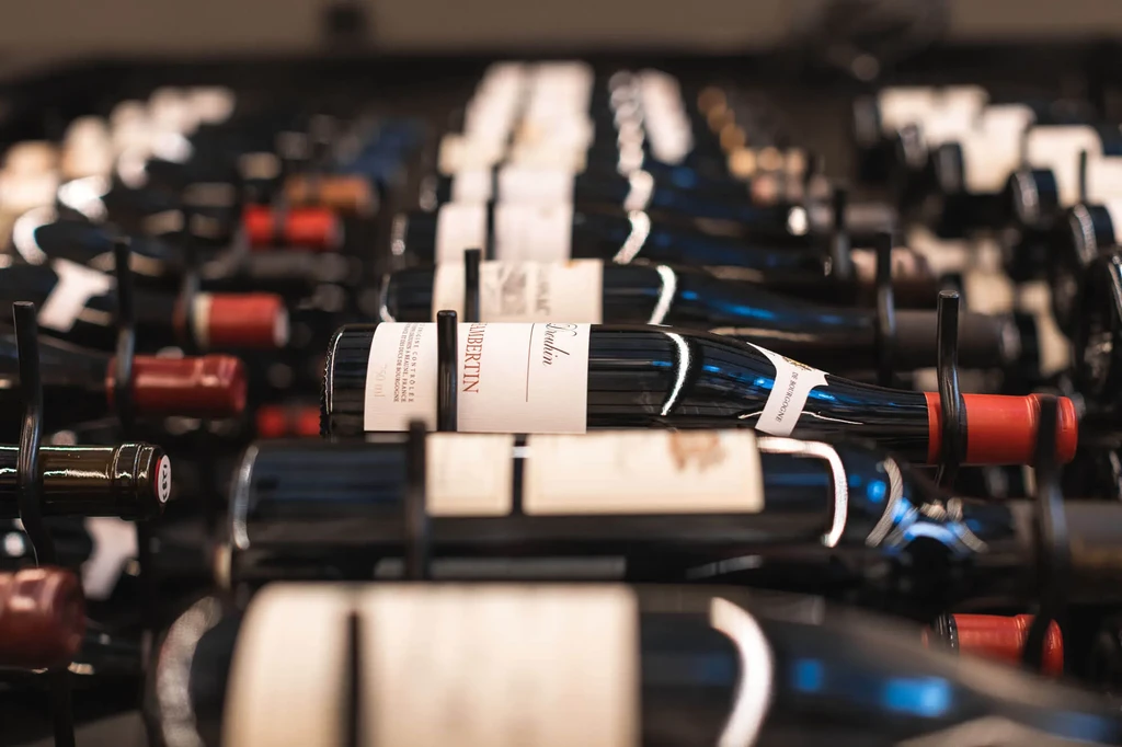 Multiple dark wine bottles in a rack, one prominently labeled LAMBERTIN.