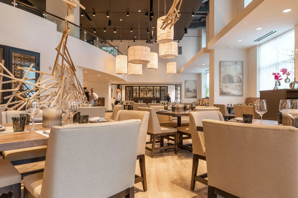 Modern restaurant interior featuring dining tables, abstract art, and a bar.