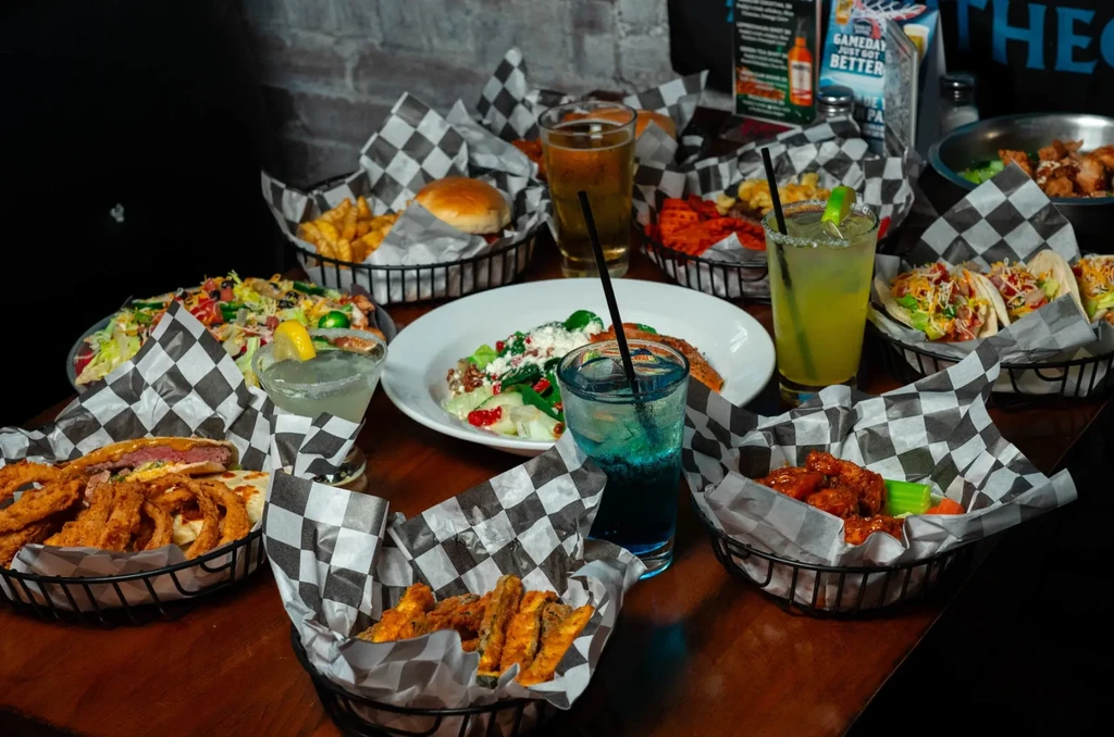 Overhead view of a restaurant table filled with various foods and cocktails.