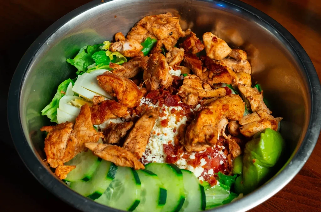 Close-up overhead view of a hearty chicken salad in a metal bowl.