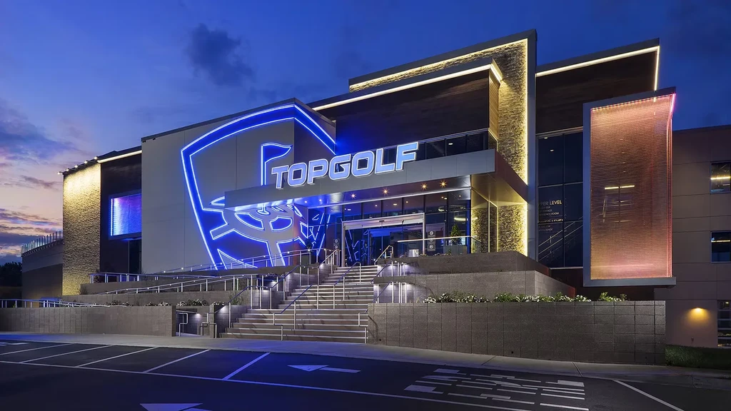 TOPGOLF building at night, brightly illuminated with a prominent blue neon sign.