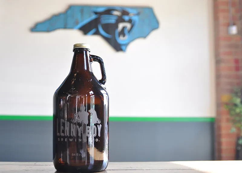 Brown glass growler with 'Lenny Boy Brewing Co.' label on wood.