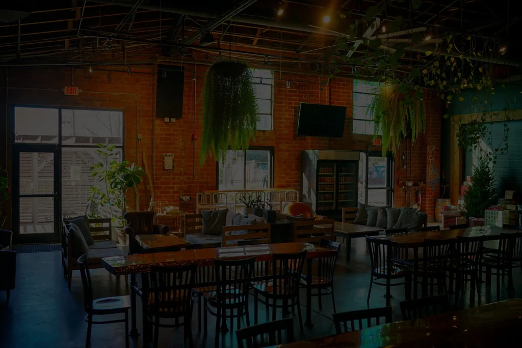 Empty, dim industrial lounge with brick, plants, and holiday decor.