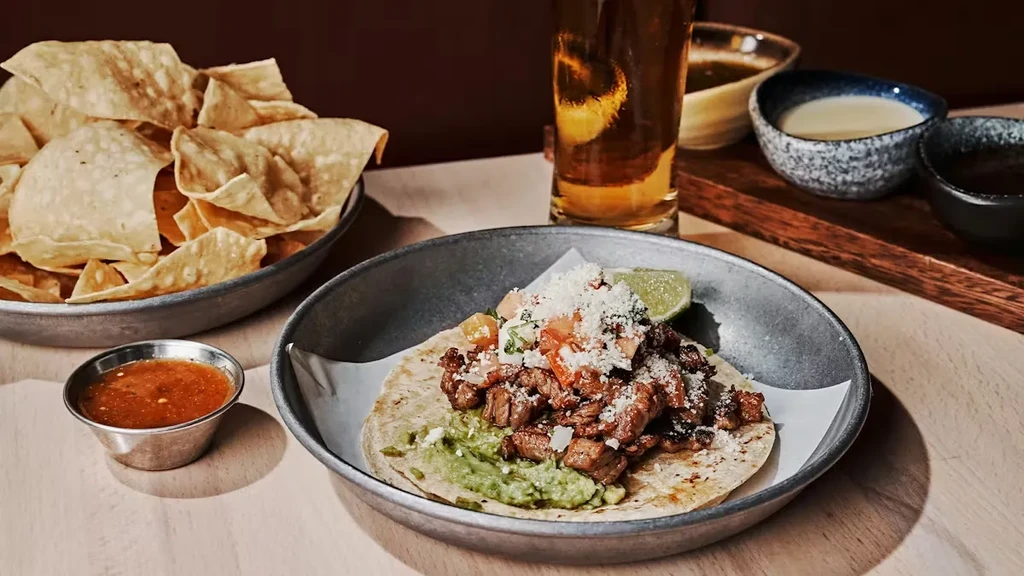Delicious taco, chips, salsa, and beer on a restaurant table.