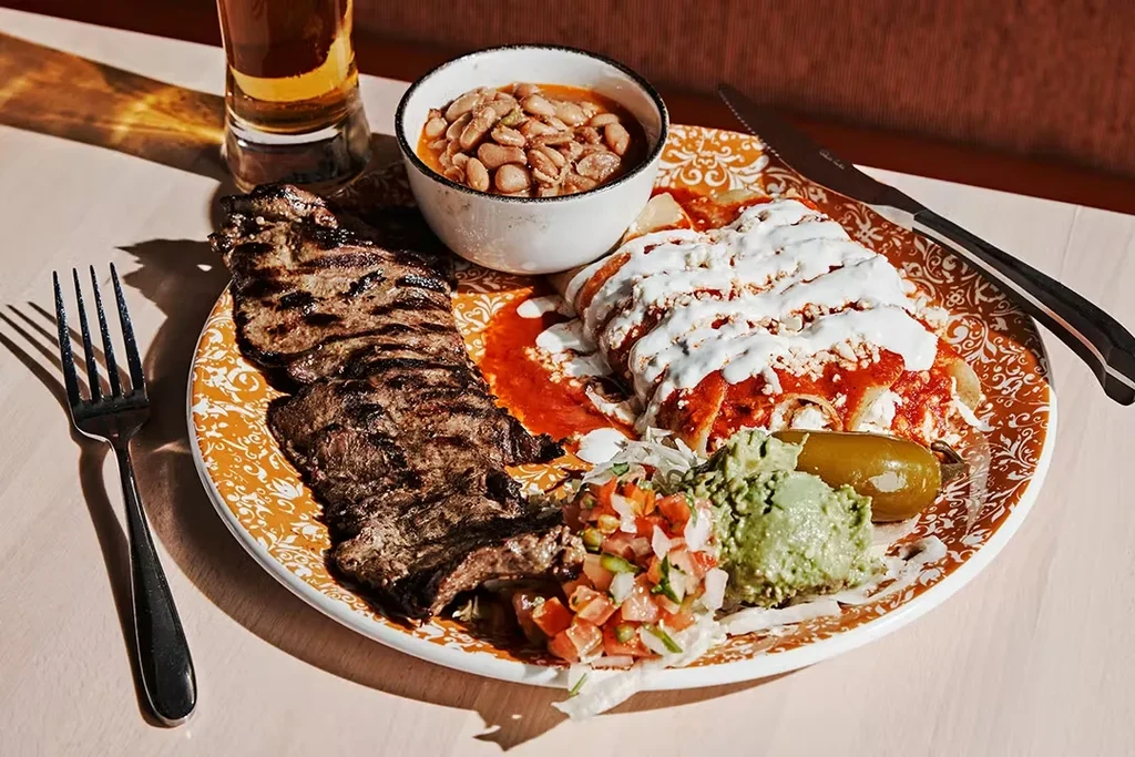 Mexican combo plate with grilled steak, enchiladas, beans, guacamole, and salsa.