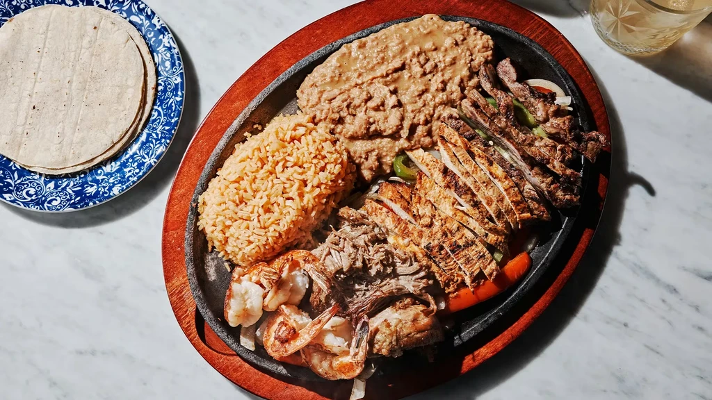 Overhead: Skillet of mixed fajitas, rice, beans, and tortillas.