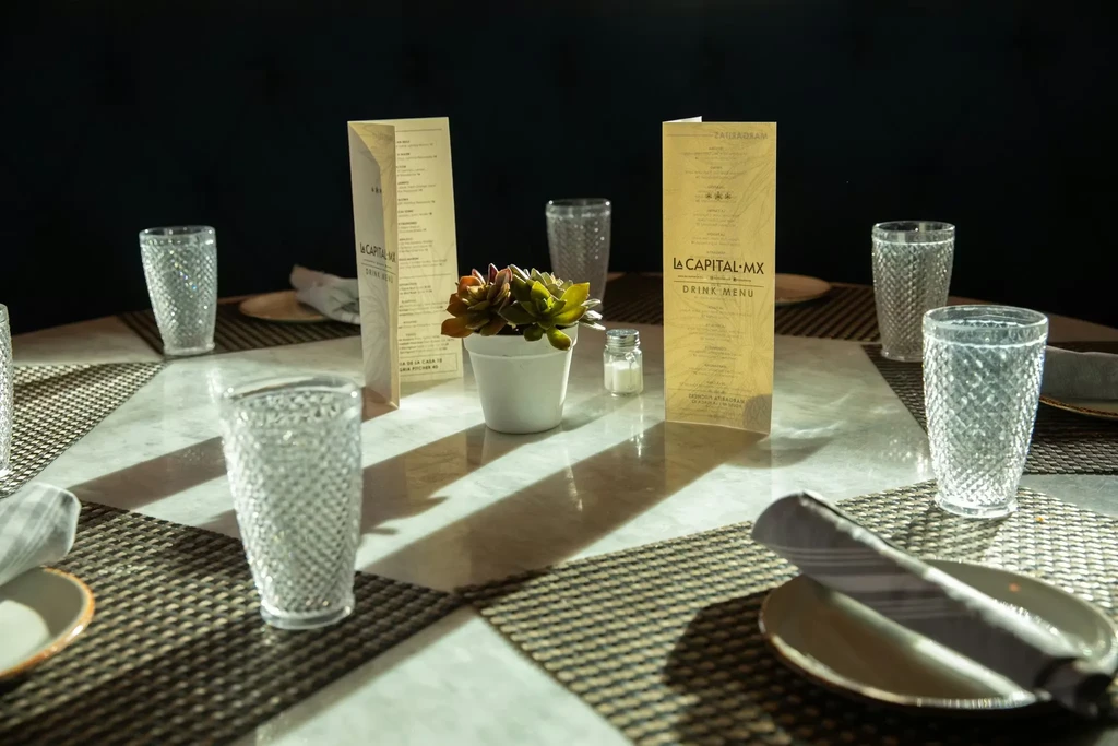 Meticulously set restaurant table with menus, placemats, and succulent plant.