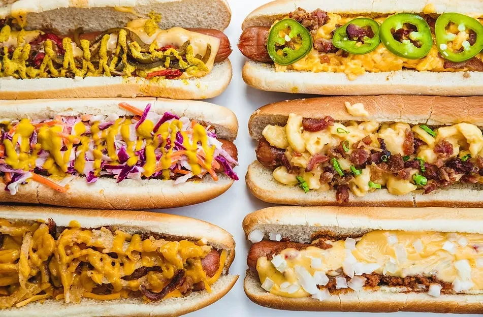 Six hot dogs with diverse toppings on a white background.