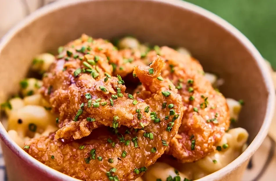 Crispy fried chicken and macaroni cheese in a bowl with chives.