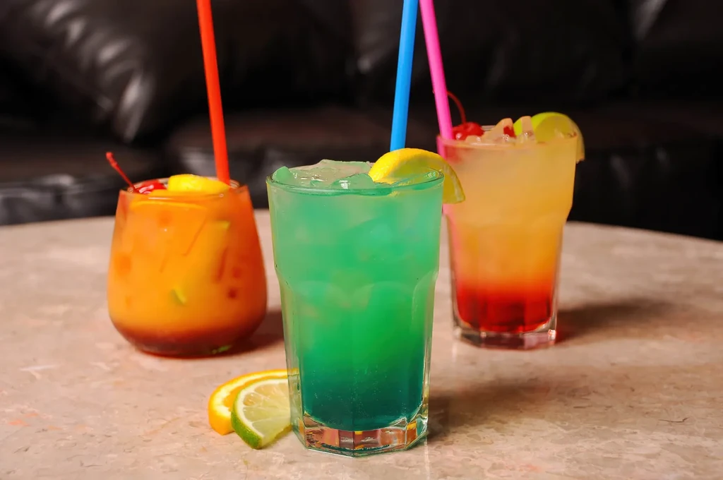 Vibrant orange, teal, and layered cocktails on a light stone table.