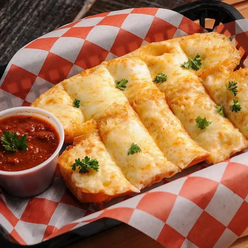 Cheesy breadsticks with marinara sauce in a checkered basket.