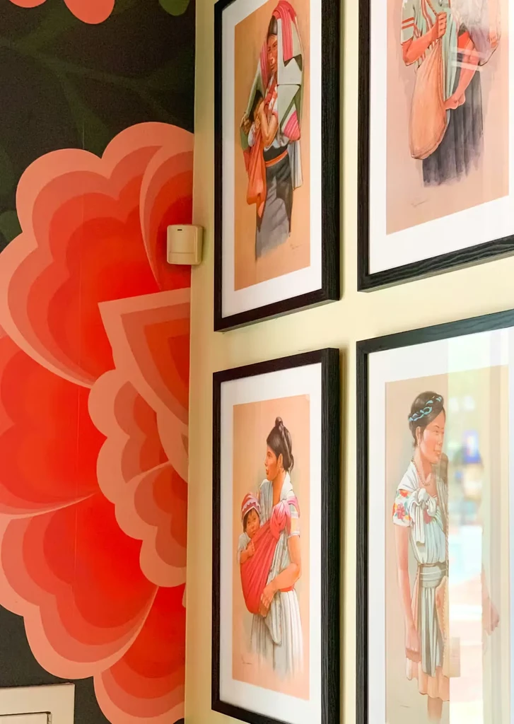 Yellow wall with framed cultural art next to a green floral mural.