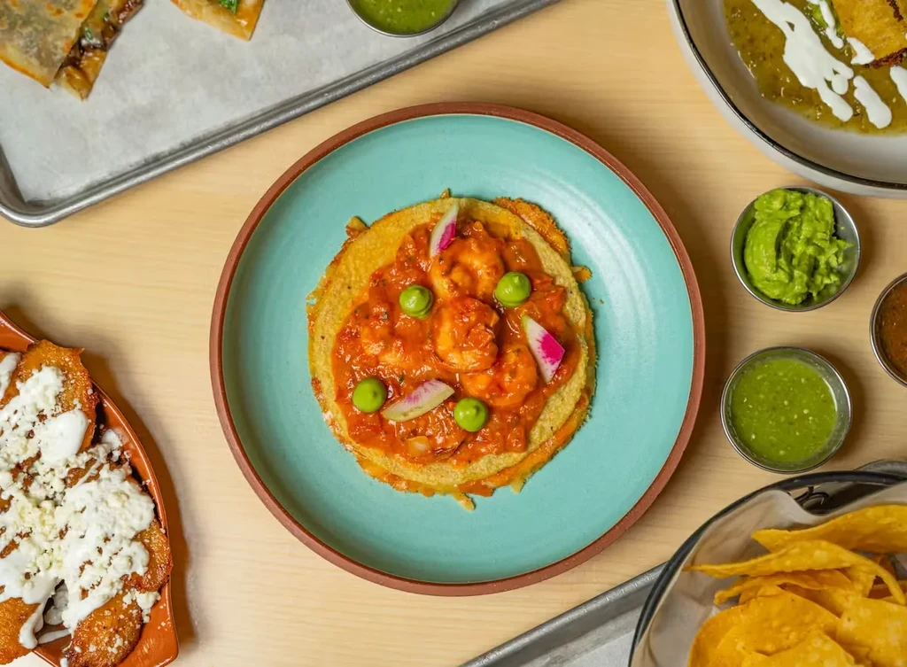 Overhead shot of a colorful shrimp dish surrounded by various Mexican foods.