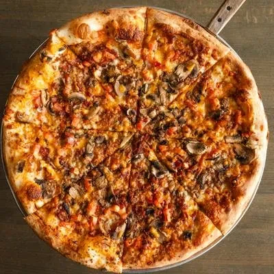 Overhead of a sliced mushroom and tomato pizza on a metal pan.