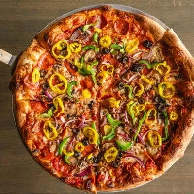 Round, fully baked pizza with pepperoni, vegetables, olives, and mushrooms.