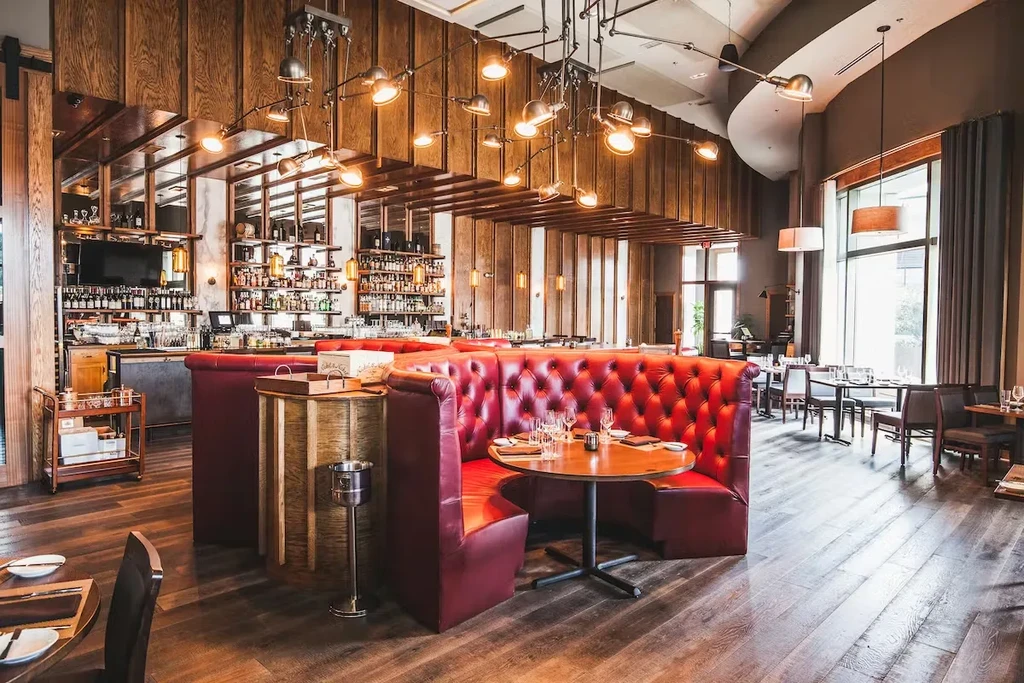 Empty, upscale restaurant interior with red booths and a well-stocked bar.
