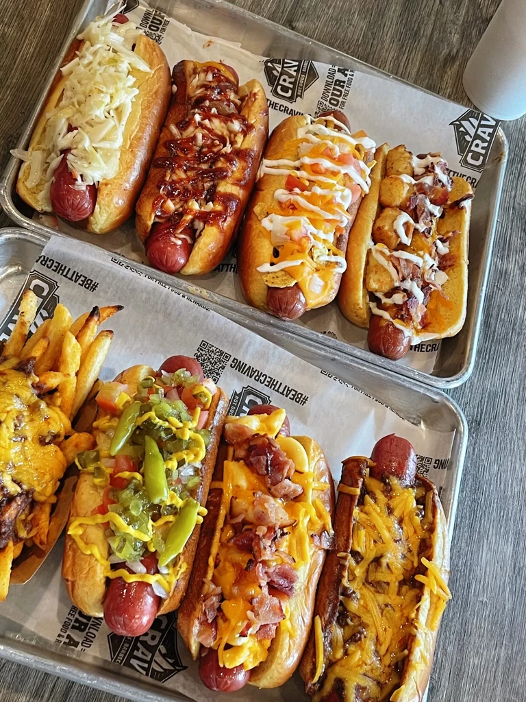 High-angle view of multiple gourmet hot dogs and loaded cheese fries.