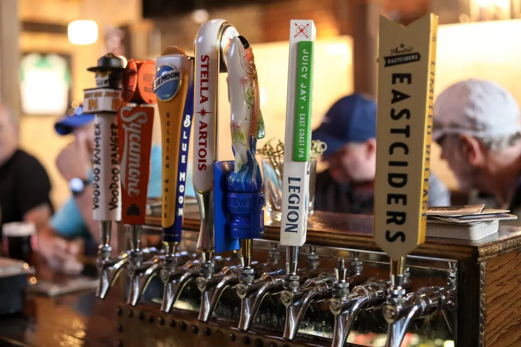 Close-up of branded beer tap handles on a wooden bar.