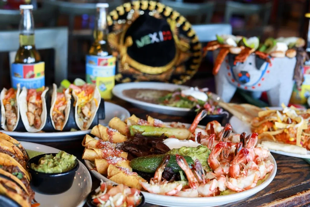 Vibrant Mexican food spread, beer, and decor on a wooden table.