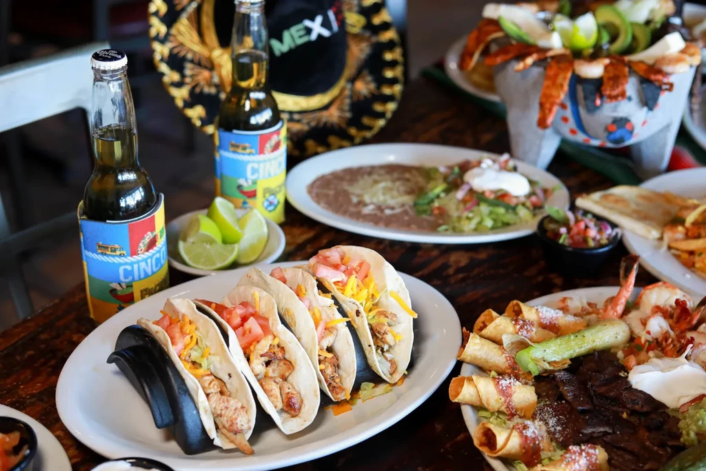 Mexican feast with tacos, grilled meats, shrimp, beer, and sombrero.
