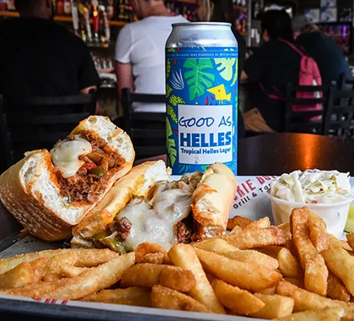 A cheesesteak sandwich, fries, coleslaw, and Good As Helles lager.