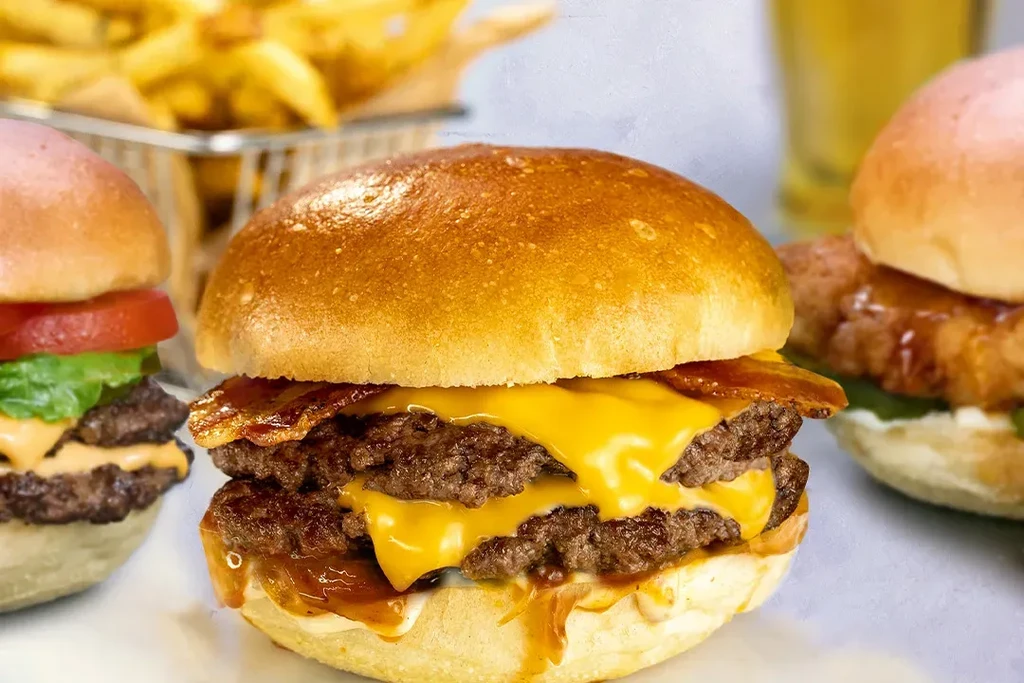 Close-up of a double-patty cheeseburger, other burgers, and fries.