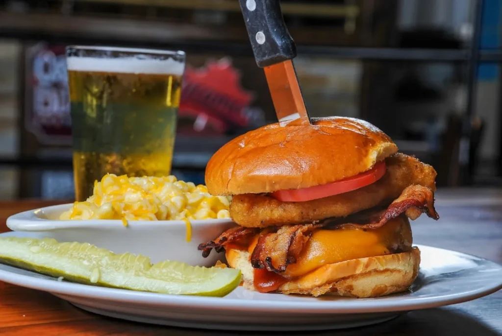 Burger with steak knife, mac and cheese, pickle, and beer.