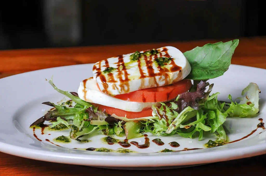 Stacked Caprese salad with mozzarella, tomato, basil, balsamic, and pesto.
