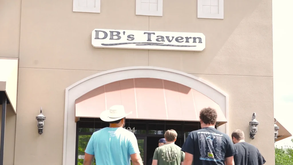 DB's Tavern entrance: arched doorway, peach awning, and people arriving.