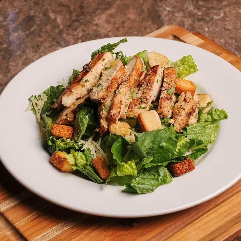 Freshly prepared grilled chicken Caesar salad with croutons and Parmesan cheese.