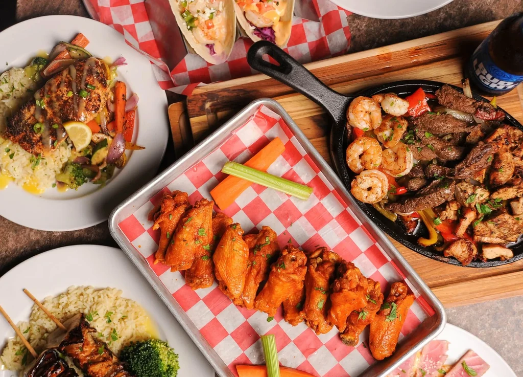 Overhead view of a table with diverse restaurant food and beer.