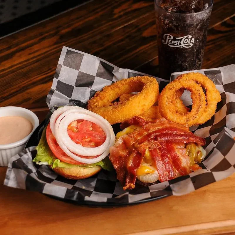 Top-down view of a burger, onion rings, pink sauce, and Pepsi.