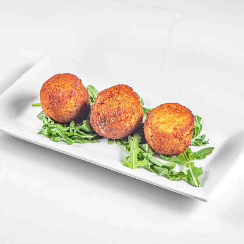 Three golden-brown fried spheres on a white plate with green leaves.