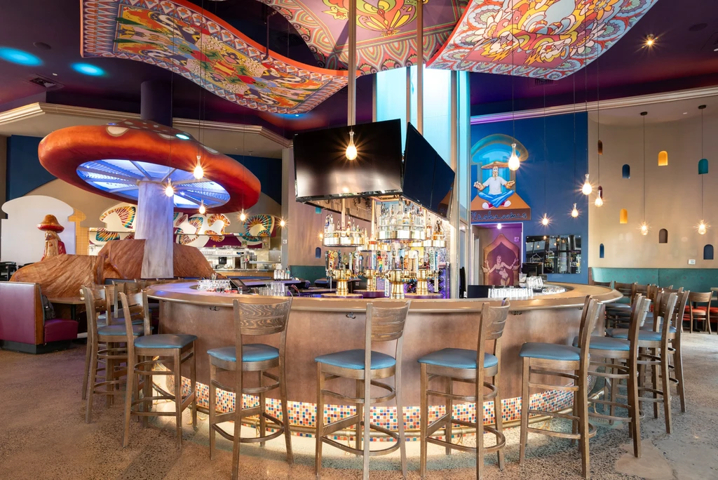 Vibrant, eclectic restaurant interior with a central bar and colorful decor.