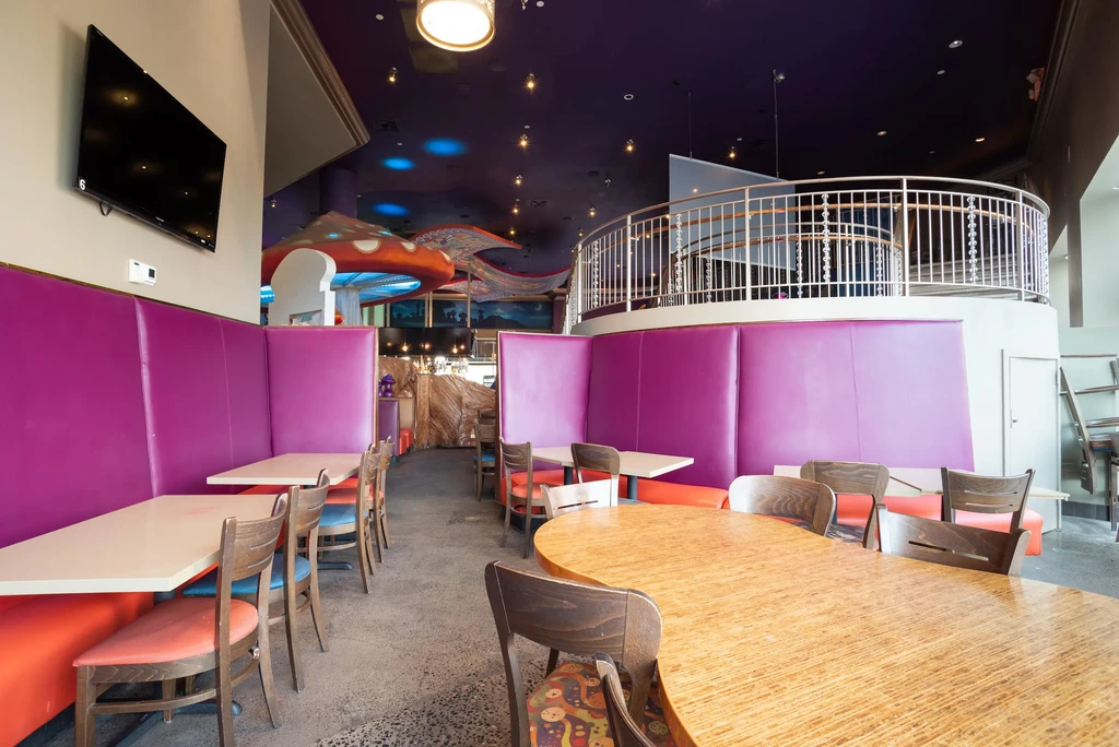 Empty vibrant restaurant interior with magenta booths and unique accent lighting.