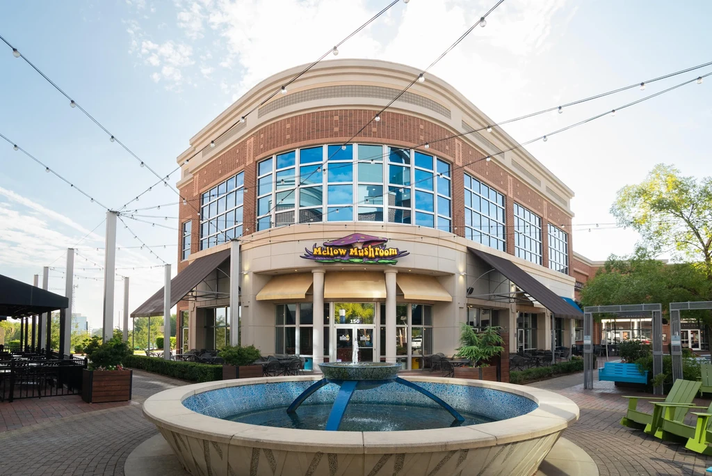 Mellow Mushroom restaurant building with curved facade in an outdoor plaza.