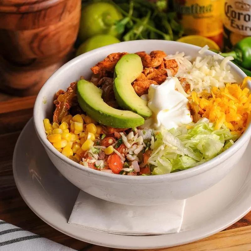 A colorful chicken power bowl topped with avocado, sour cream, and fresh ingredients.