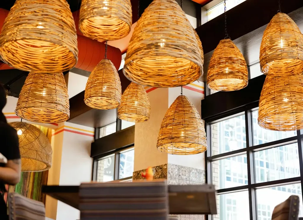 Woven rattan pendant lights illuminate a warm restaurant interior.