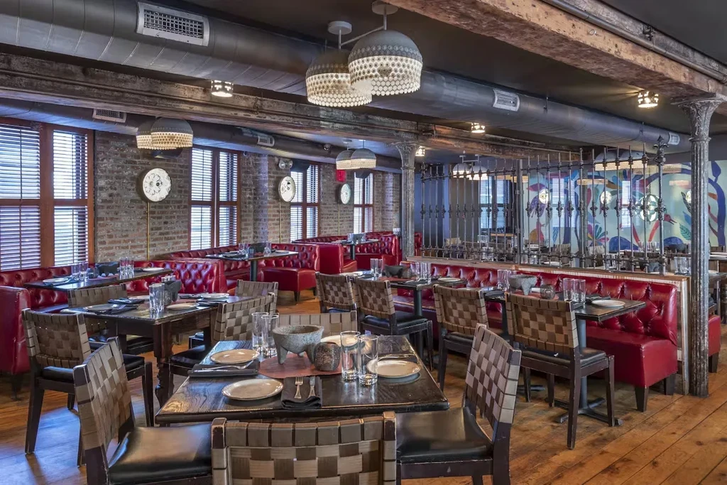 Empty industrial-style restaurant with red booths, brick walls, and colorful mural.