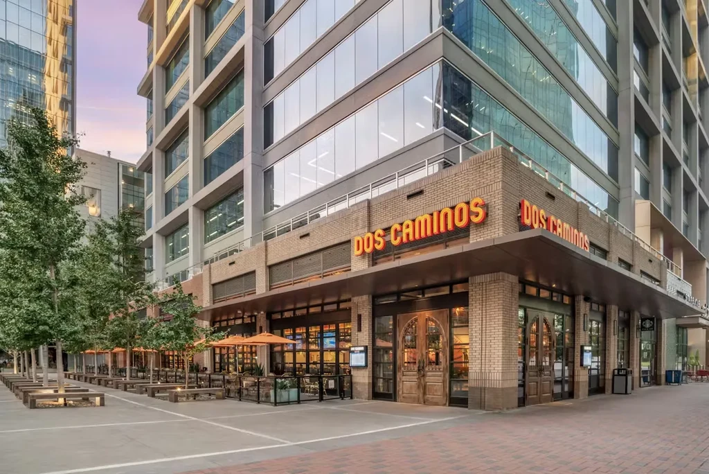 Dos Caminos restaurant facade with outdoor seating and orange umbrellas.