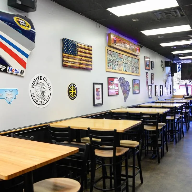 Empty casual restaurant interior with high-top tables and sports decor.