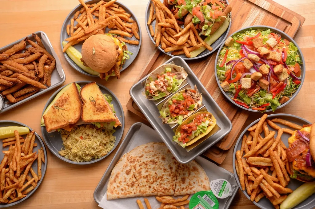 Overhead view of a wooden table laden with various casual foods.