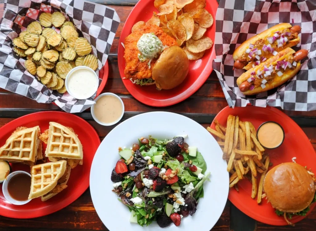 Rustic wooden table seen from above, laden with varied comfort foods.