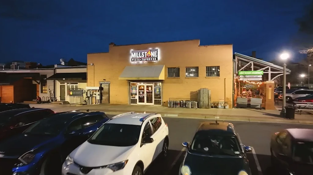 Illuminated Millstone Pizza and Old Town Market at night with patrons.