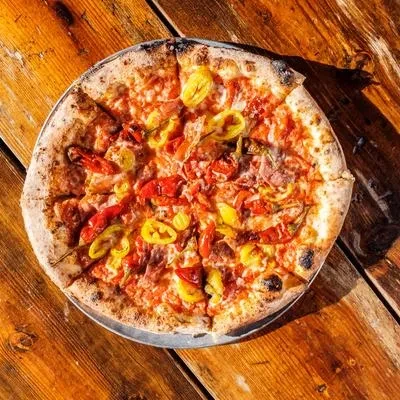 Freshly baked pizza with peppers on a rustic wooden table.