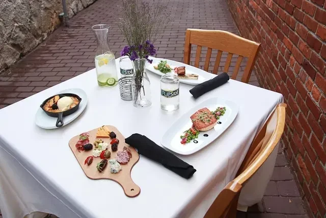 Elegant outdoor table set with dessert, charcuterie board, and main courses.