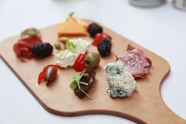 Meticulously arranged charcuterie board with diverse cheeses, meats, and produce.