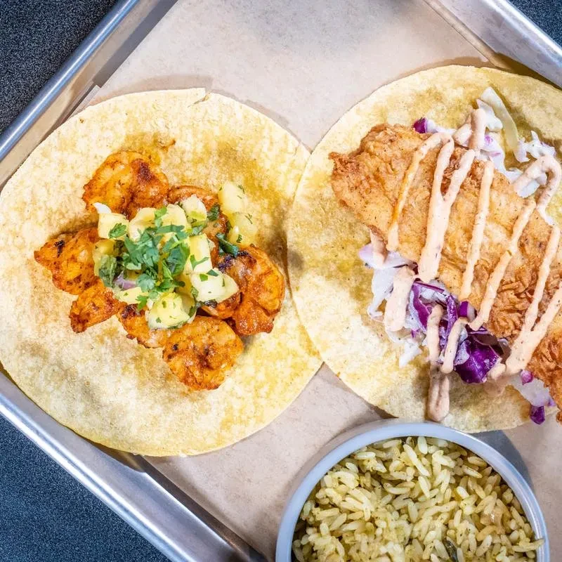 Top-down photo of shrimp and fried fish tacos with seasoned rice.