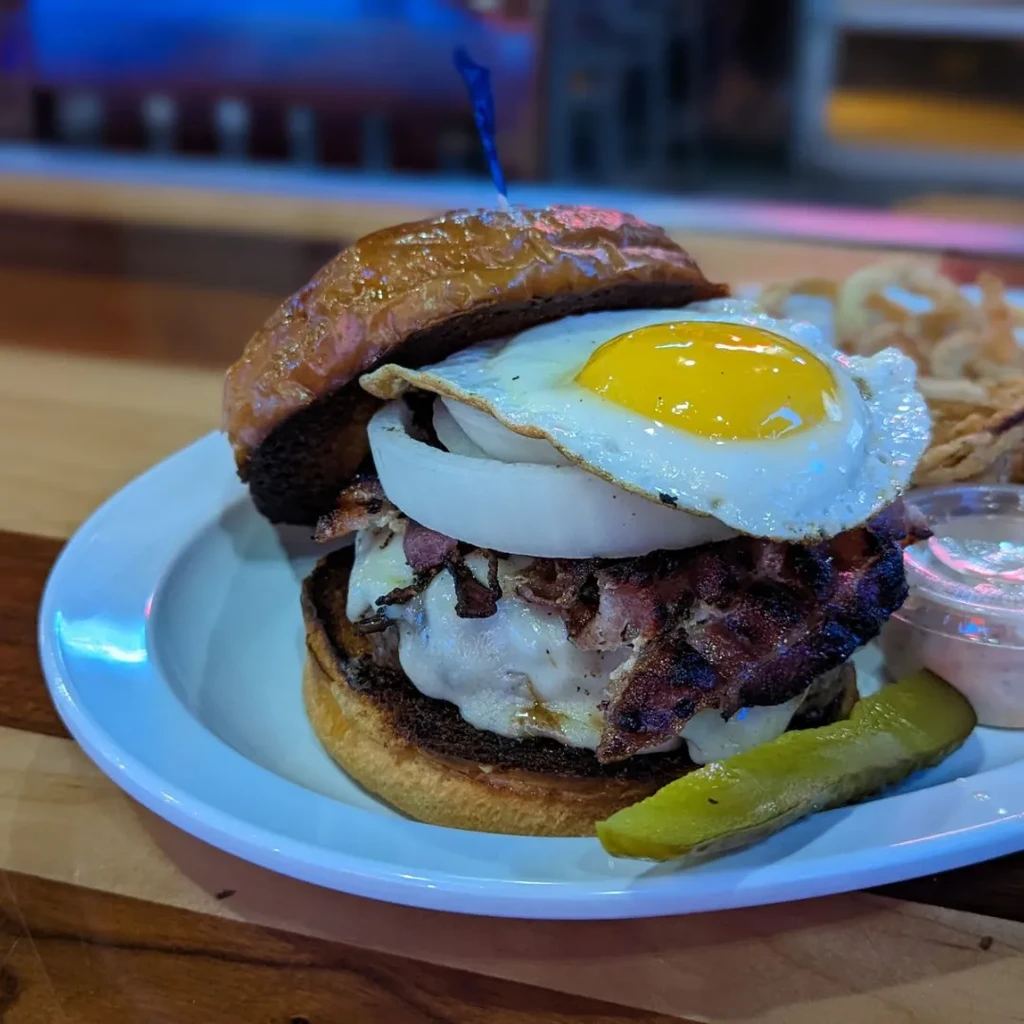 Burger with fried egg, bacon, melted cheese, and onion.
