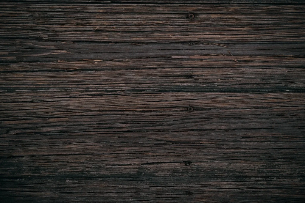 Close-up of dark, rustic wooden planks with visible grain, cracks, and knots.